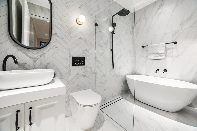 Bright bathroom with oak vanity, green tiles and freestanding bath