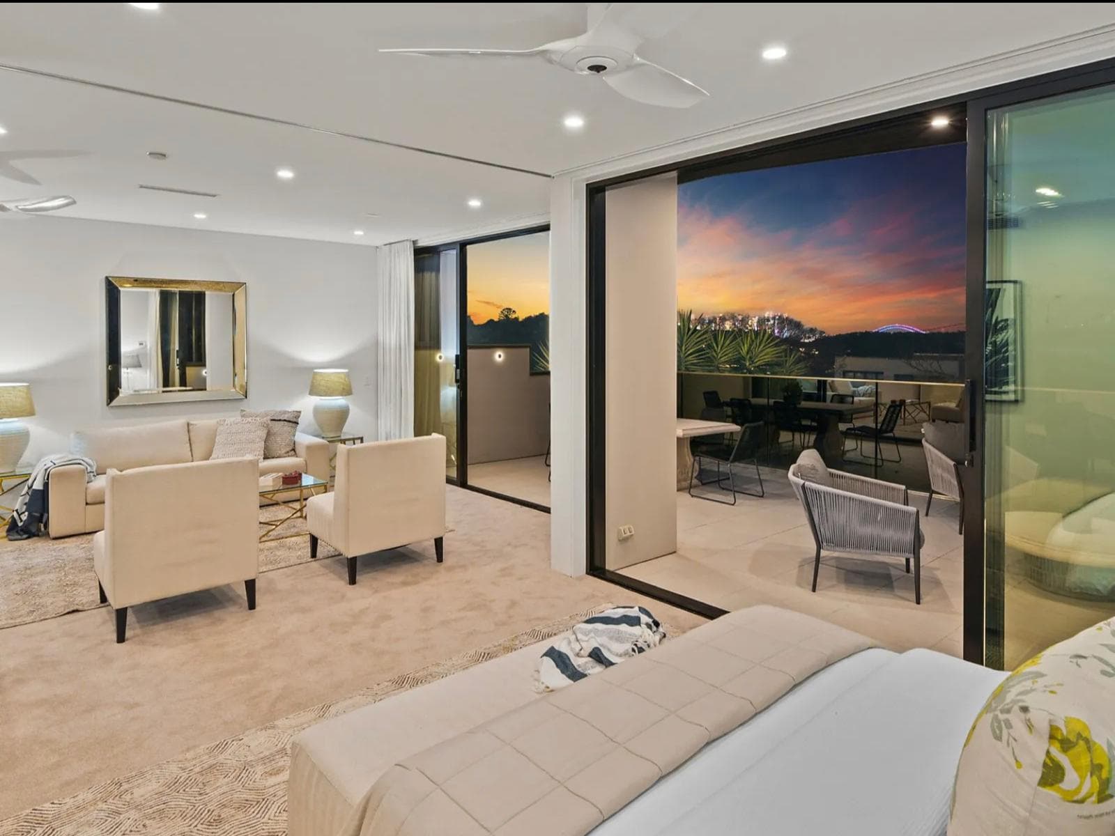 Bedroom sitting area in Sydney opening to a terrace at sunset through glass doors