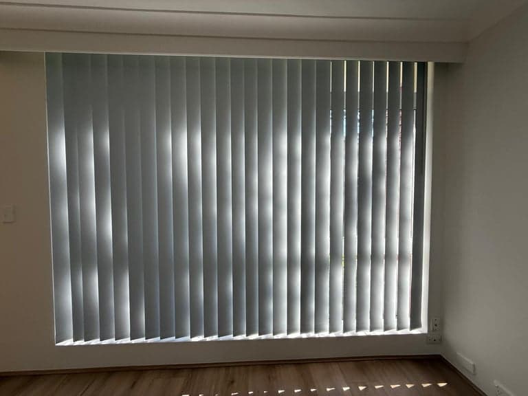 White vertical blinds filtering daylight across a Sydney window