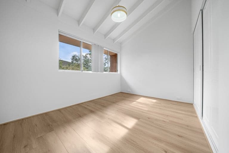 Light oak hybrid flooring in a vaulted Sydney bedroom with a clerestory window