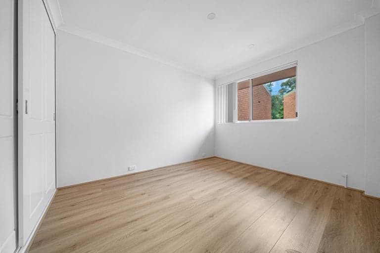 Light oak flooring in a Sydney bedroom with a high window and built-in wardrobe