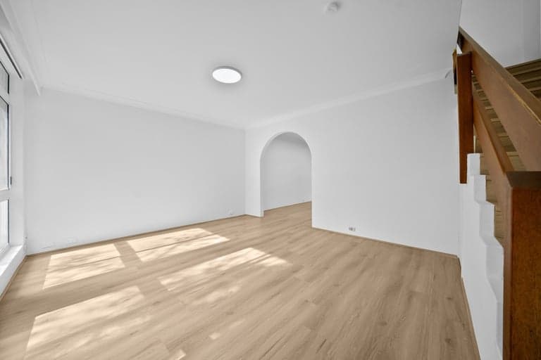 Light oak flooring through a Sydney living room with an arched doorway and timber stair rail