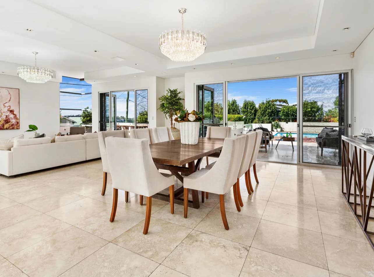 Open dining room with warm oak timber flooring and white kitchen