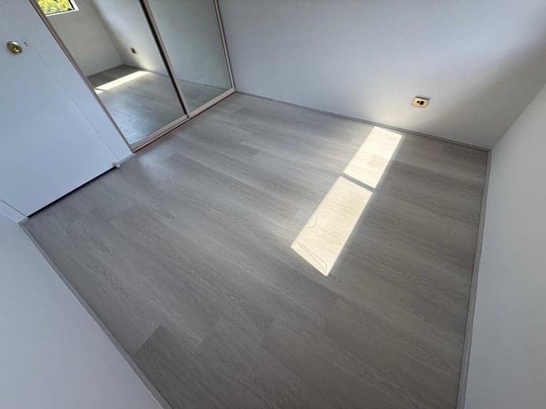 Pale grey hybrid flooring installed in a Sydney bedroom with mirrored wardrobe doors