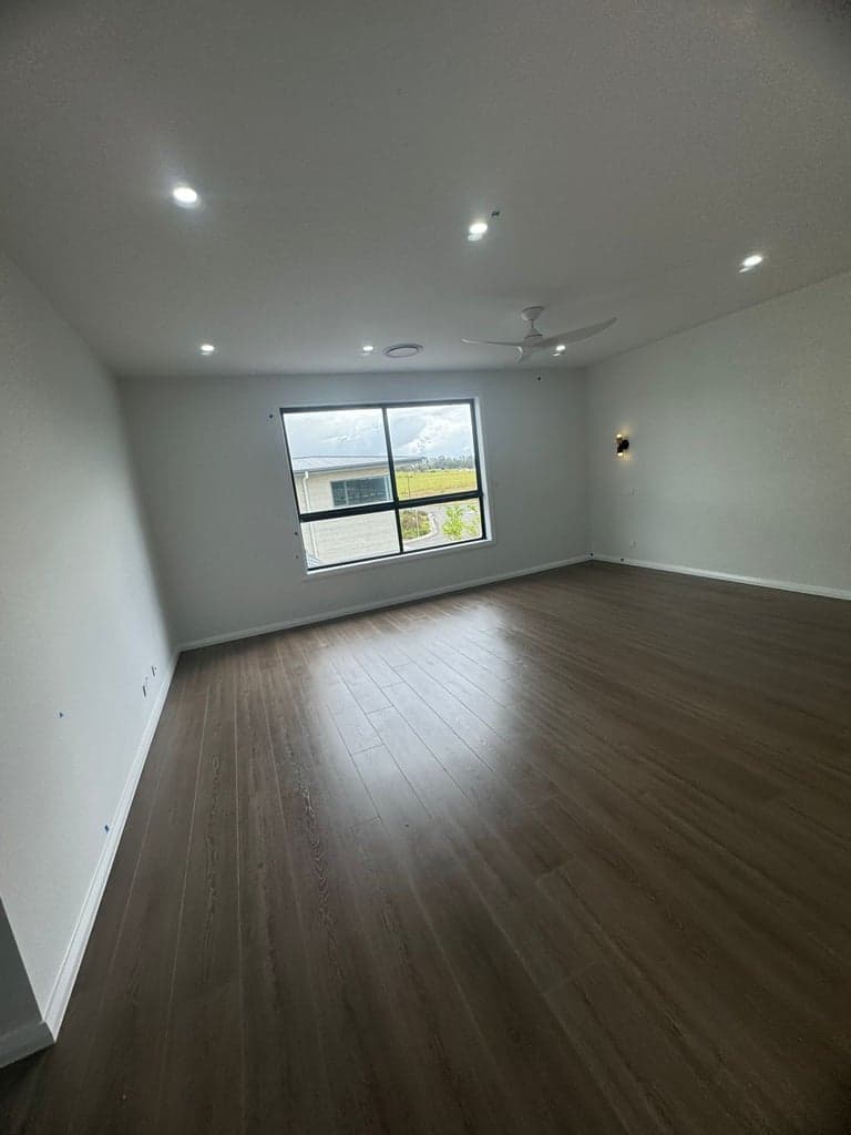 Dark oak hybrid flooring in an empty Sydney bedroom with a ceiling fan