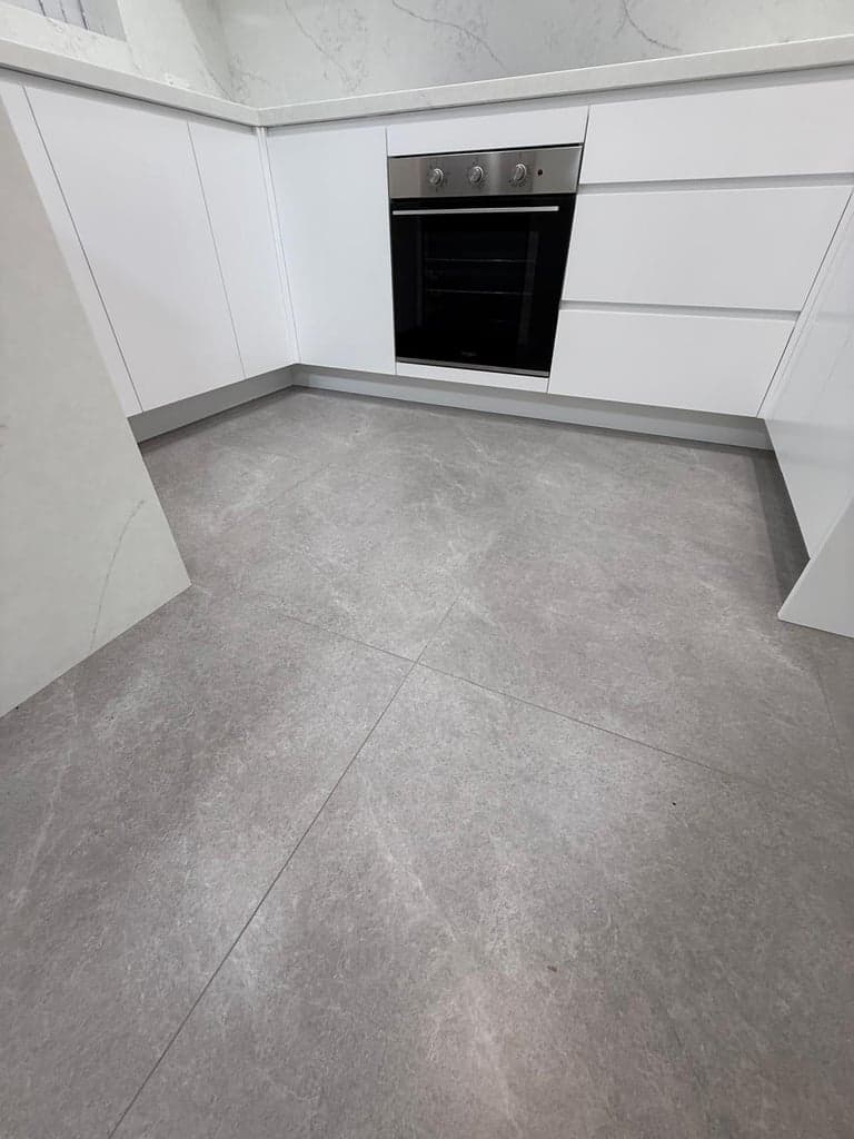 Large-format grey stone tiles on a Sydney kitchen floor with white joinery