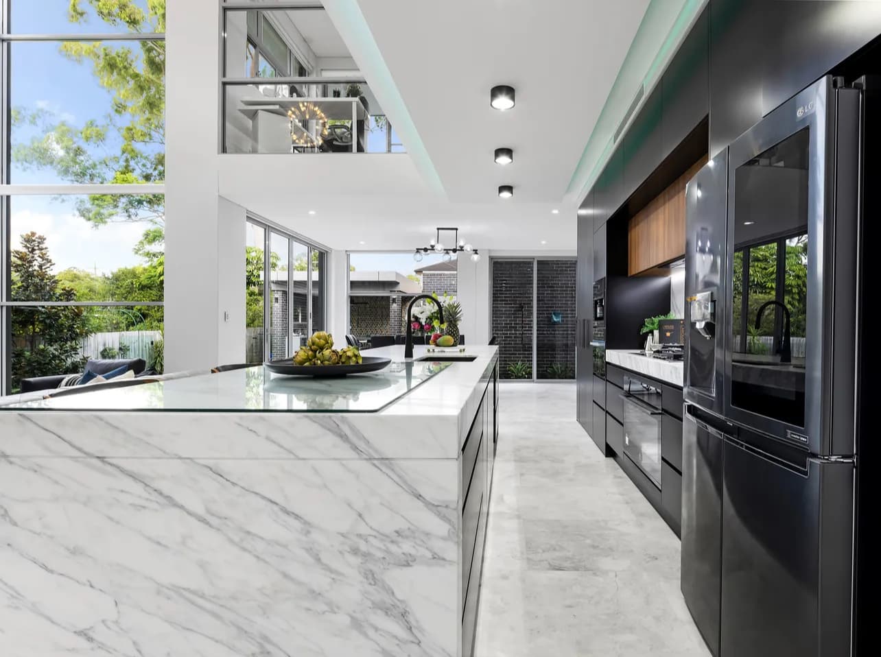 Open Sydney kitchen with marble island, black cabinetry and timber stools