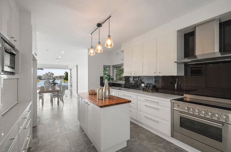 White kitchen island with a timber top facing Sydney harbour views