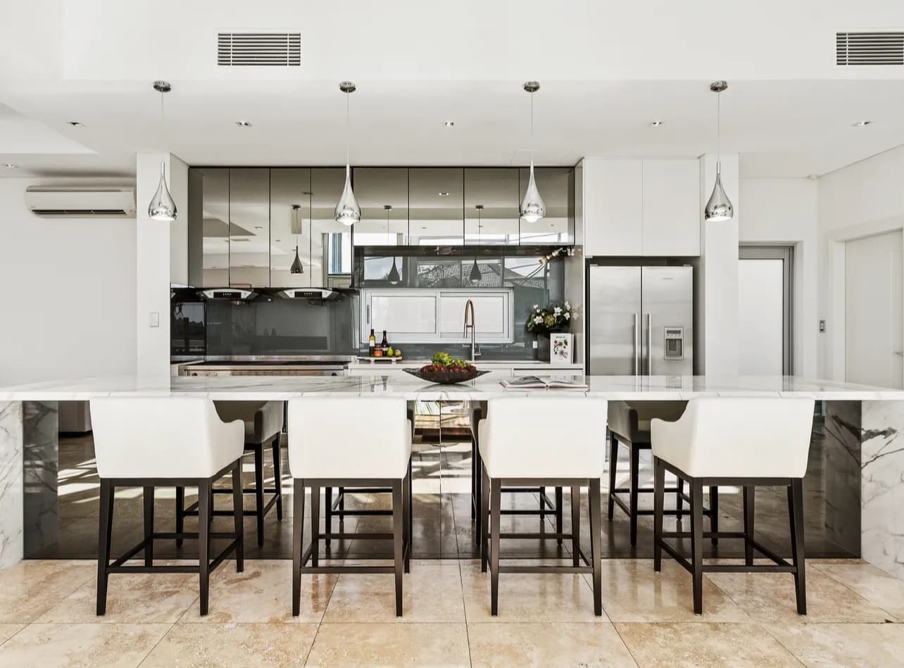 Open Sydney kitchen with marble island, black cabinetry and timber stools