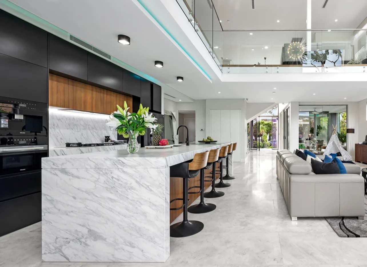 Sydney double-height kitchen renovation with a marble island, black joinery and timber bar stools