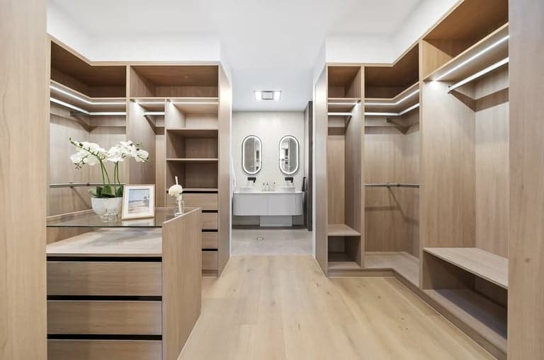 Walk-in oak wardrobe in Sydney with island drawers and LED strip lighting