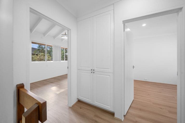 Custom white hallway cupboard in a Sydney home with light oak floors