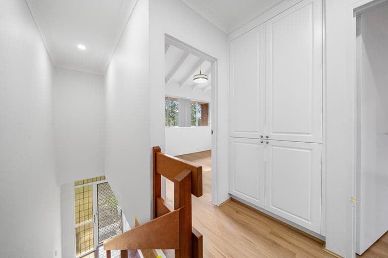 Built-in white landing cupboard beside a timber stair rail in Sydney
