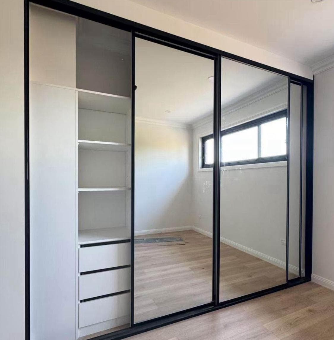 Black-framed mirrored sliding wardrobe in Sydney with open white shelving