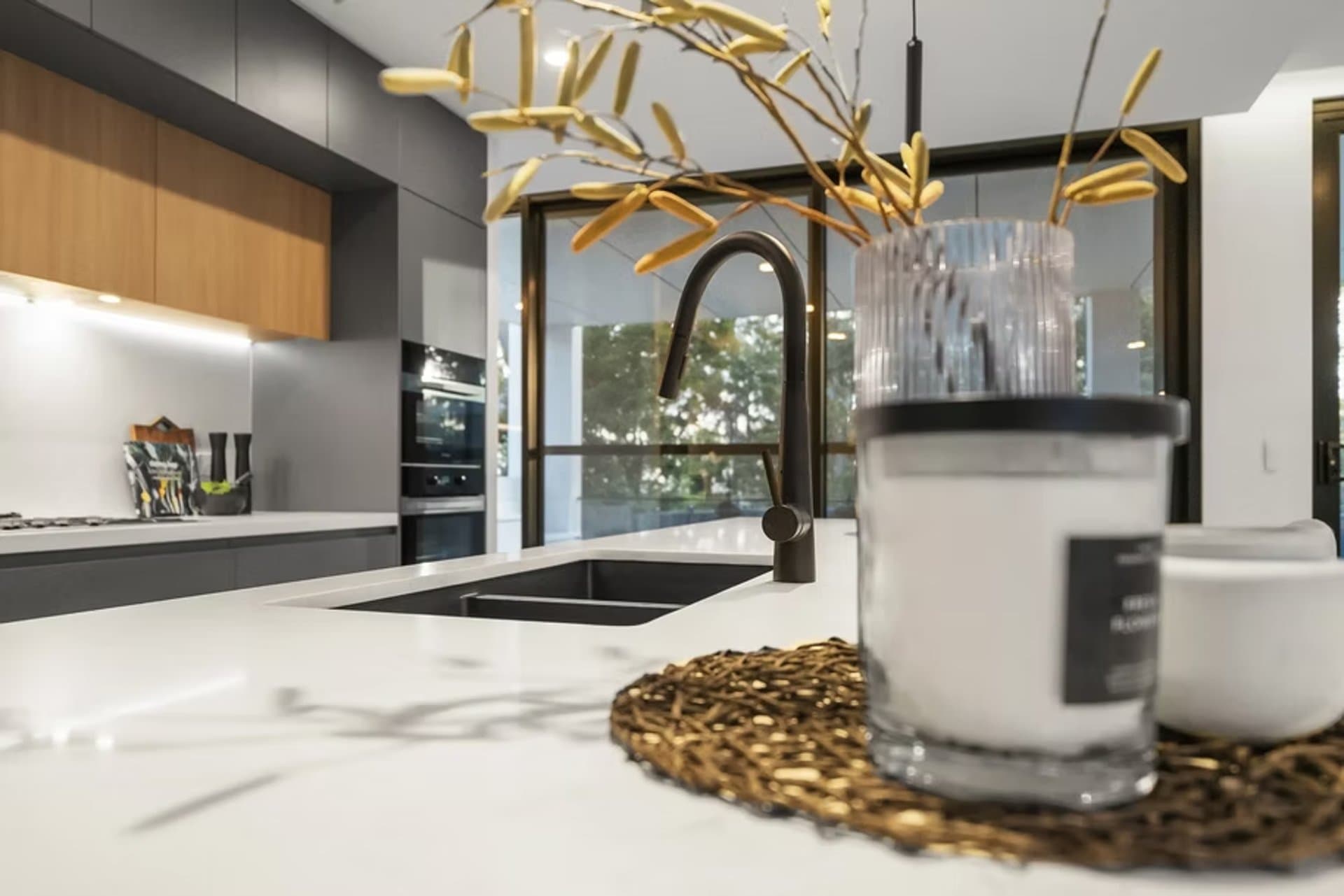 Stone kitchen island close-up in Sydney with a black mixer and oak cabinets