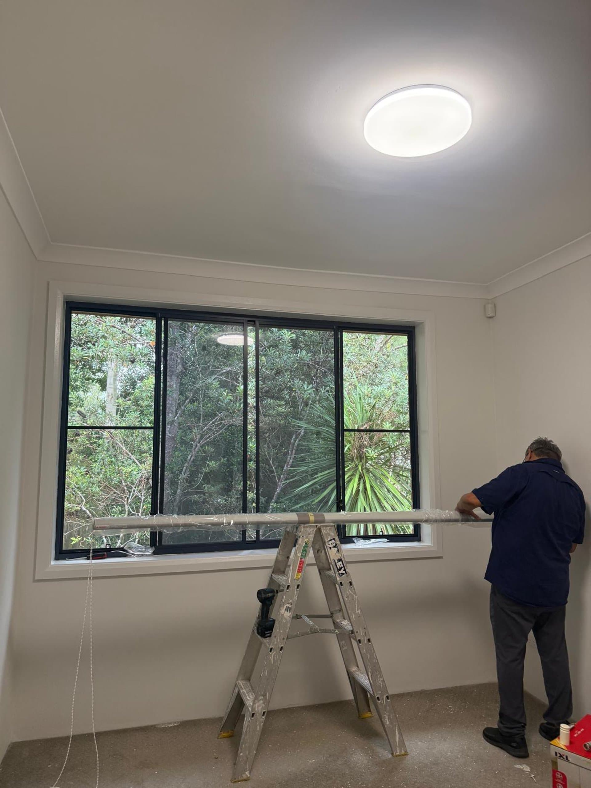 Made-to-measure curtain track being fitted to a black-framed Sydney window