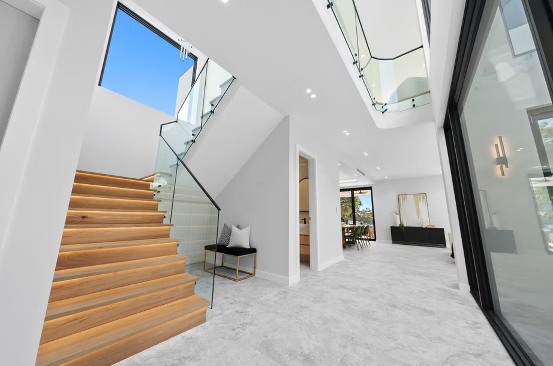 Sydney foyer with stone floors, oak stairs and a glass balustrade