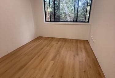 Light oak hybrid flooring in an empty Sydney bedroom with a garden window